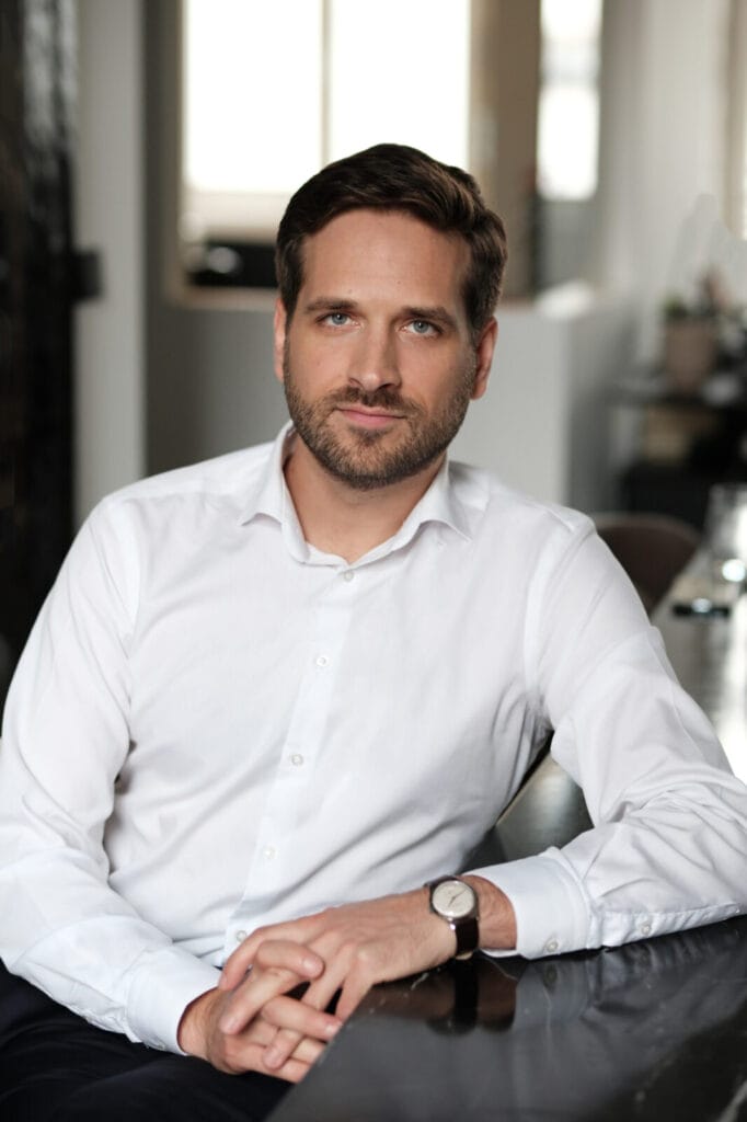 Mann in weißem Hemd sitzt am Tisch.